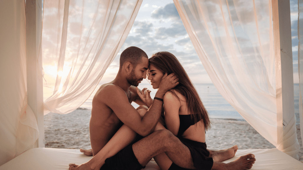 A man and a woman sitting in bed with their legs intertwined sharing rekindled sexual intimacy.