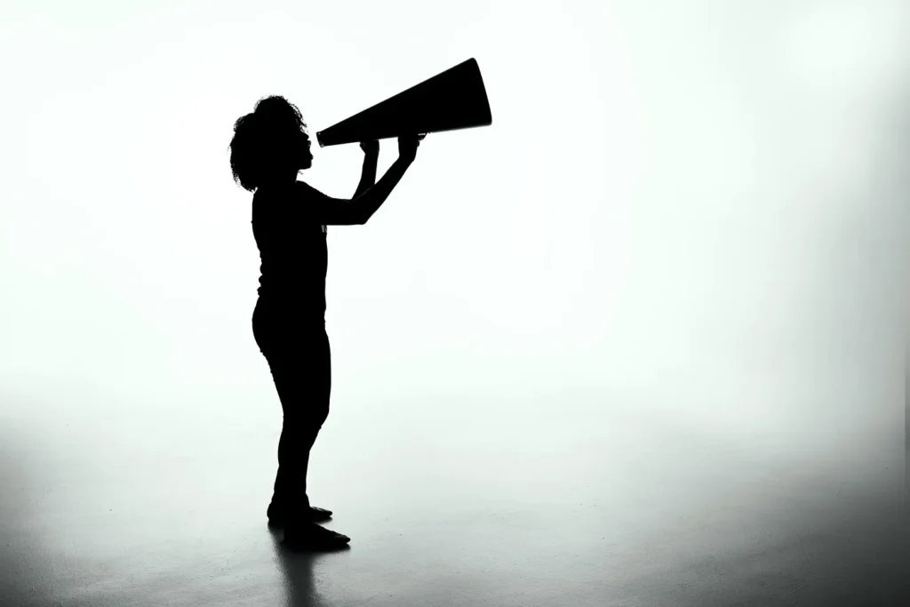 Silhouette of a woman using a megaphone, representing the amplified effects of echo chambers in digital communication.




