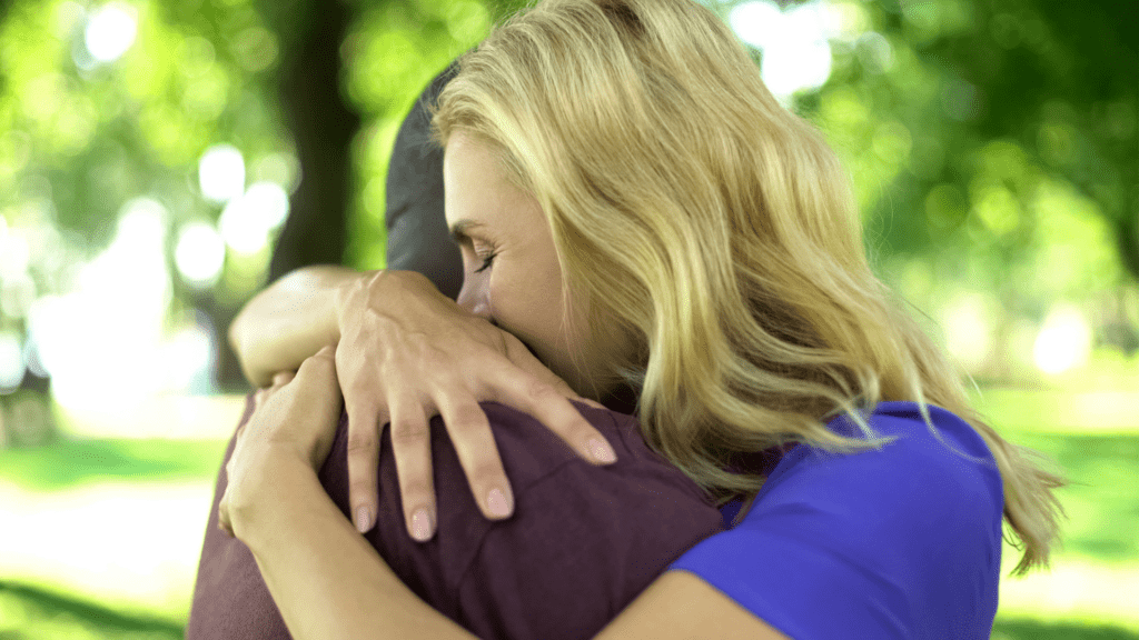 Woman hugging her partner in a park, highlighting emotional vulnerability.