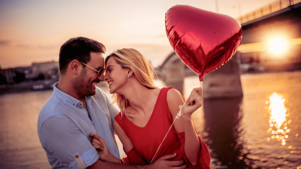 Couple holding a heart balloon at sunset, symbolizing emotionally feral relationships.