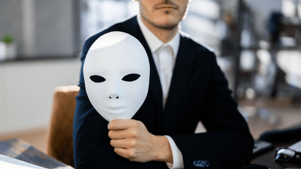 A man in a suit holding a white mask, symbolizing deception and hidden truths.


