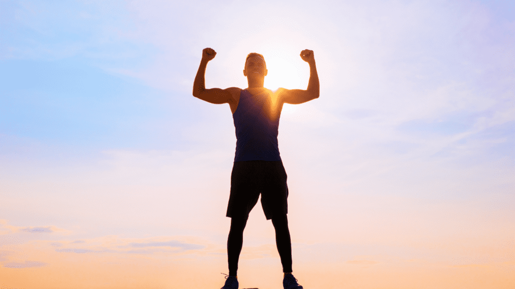 Person celebrating success with arms raised at sunset, representing discipline and self-control



