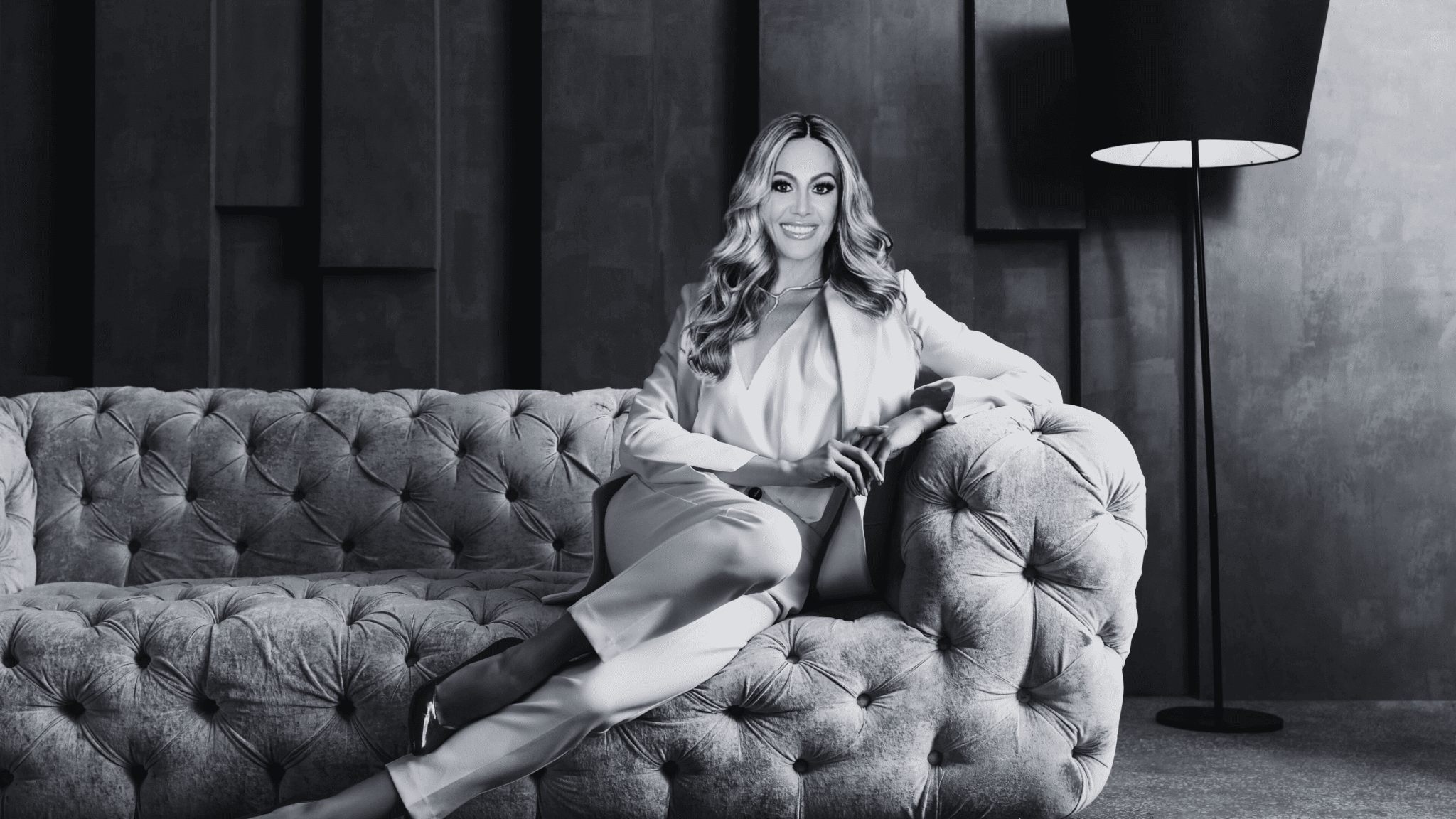 Dr. Sydney Ceruto, founder of MindLAB Neuroscience, sitting thoughtfully on a tufted couch, embodying expertise in neuroscience-based coaching and personal transformation