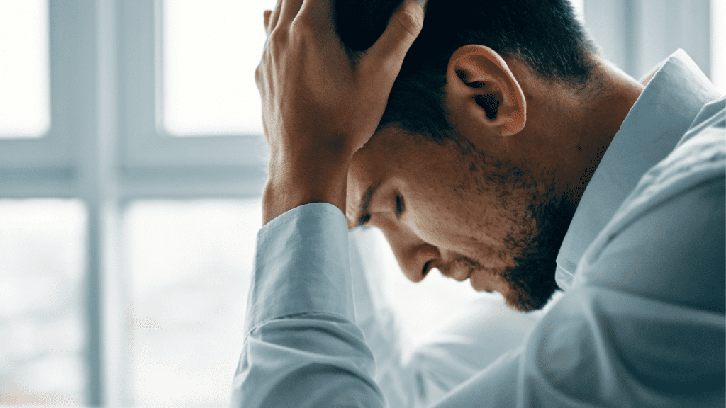 Man holding his head in frustration, appearing to be overwhelmed from nervous system dysregulation.