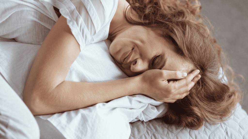 Woman experiencing emotional pain from being incapable of emotional availability in white bedding.

Description: A woman lies in white bedding, appearing peaceful and relieved, with her hand partially covering her smiling face. The image suggests emotional release and the comfort that comes with self-discovery and healing.
