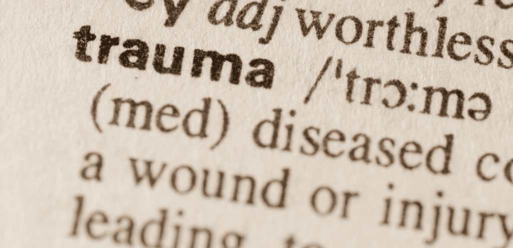 Close-up of the word 'trauma' in a dictionary, emphasizing its definition.

