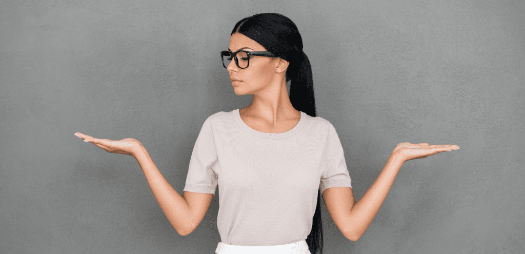 A thoughtful woman weighing options with her hands, symbolizing the choice between mental health coaching and therapy. 