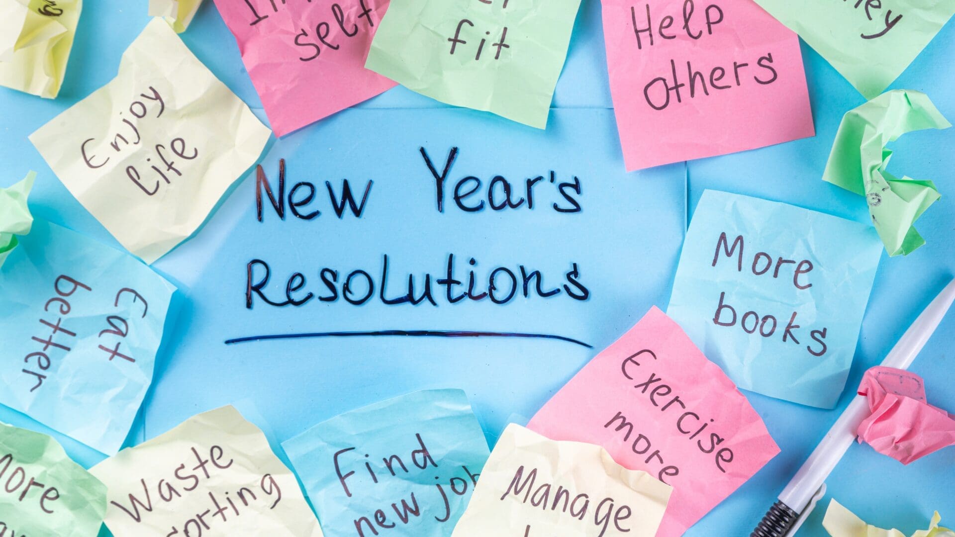 Handwritten New Year’s resolutions on colorful sticky notes with goals like help others, exercise more, and eat better.