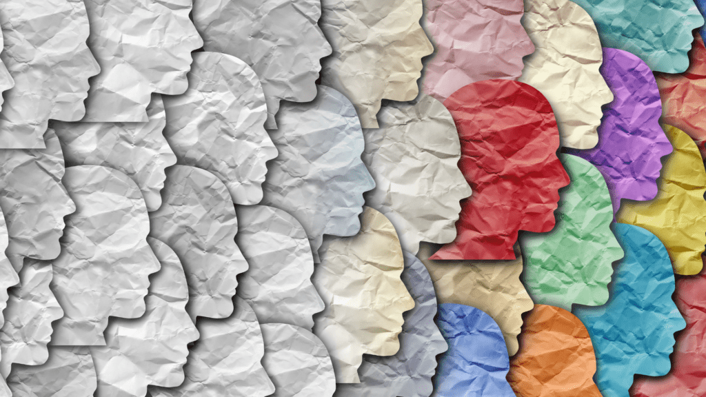 Profiles of diverse faces made of crumpled paper in various colors, symbolizing individuality and personal growth. 