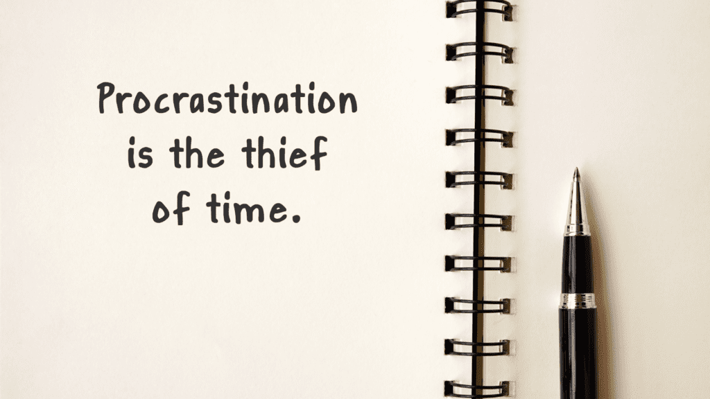 Open notebook with the phrase "Procrastination is the thief of time" written on a page.


