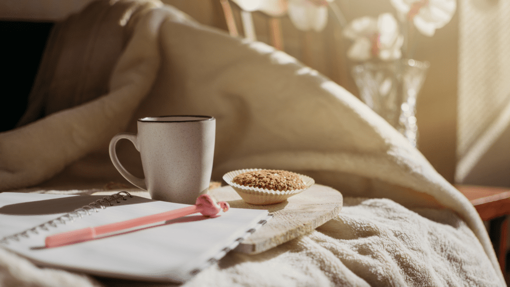 Morning journal with coffee mug and muffin in warm sunlight.

