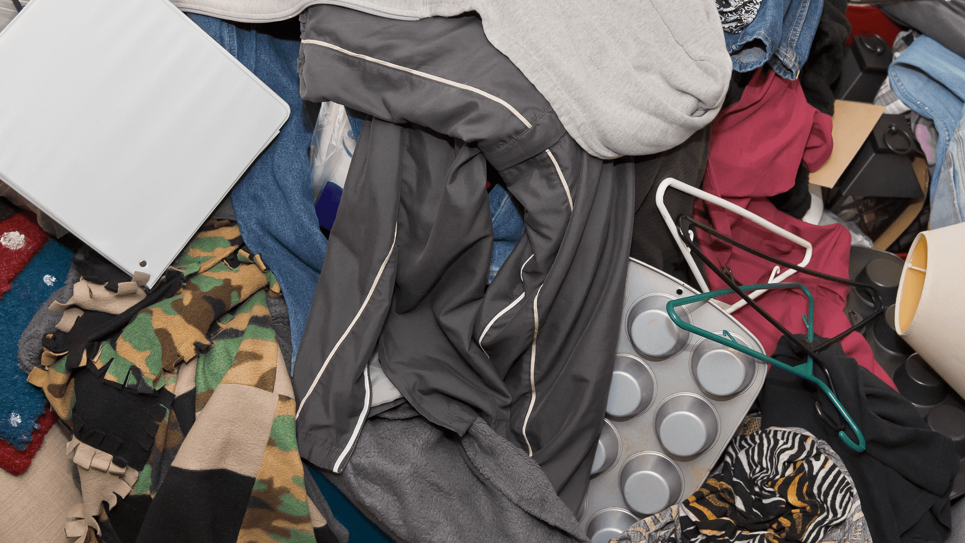 Cluttered pile of clothes, hangers, and household items representing hoarding disorder.