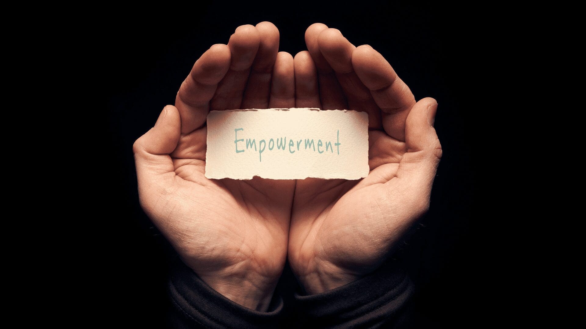 A pair of hands gently holding a torn piece of paper with the word Empowerment written on it, symbolizing personal strength and self-growth.