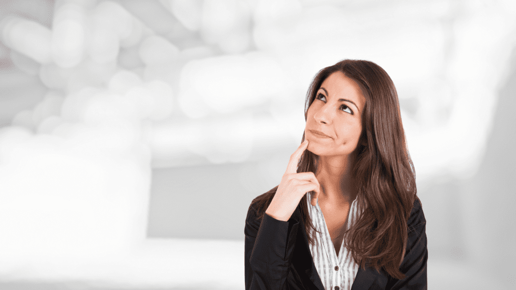 A thoughtful woman in business attire looking up in contemplation, representing self-reflection and overcoming polarized thinking.

