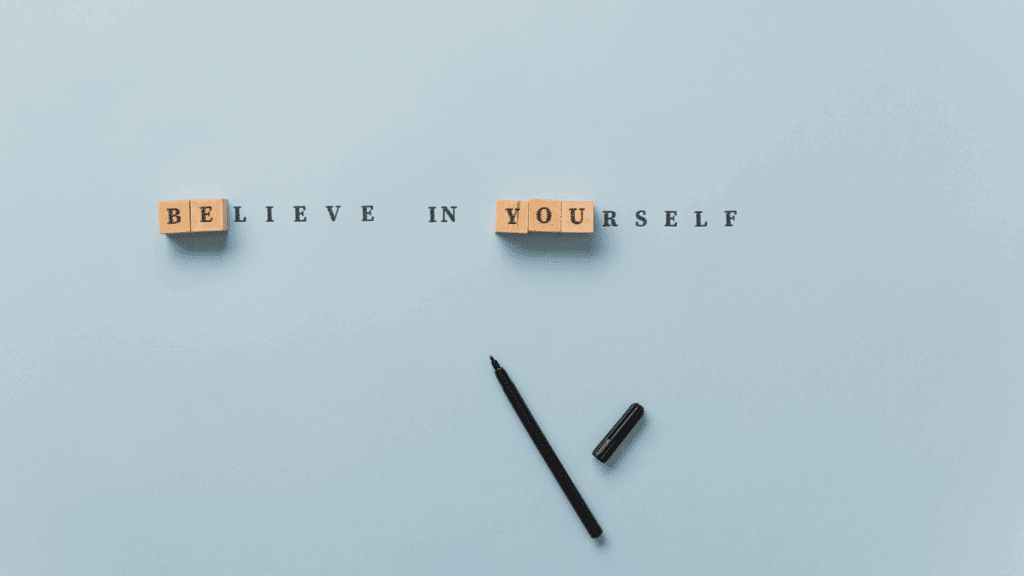 The Science of Intuition: How to Trust Your Gut Without Second-Guessing 1 Wooden letter blocks spelling "Believe in Yourself" on a minimalist blue background with a black pen beside them.