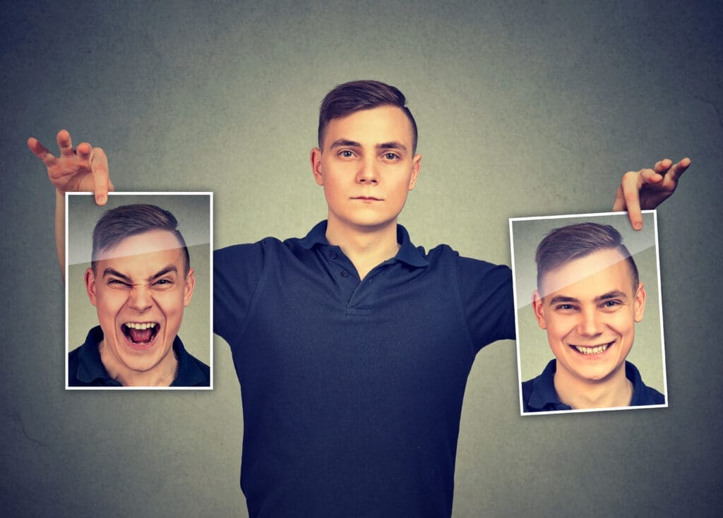 A man holding two identical portraits, symbolizing shifting perceptions of others in idealization and devaluation cycles. 