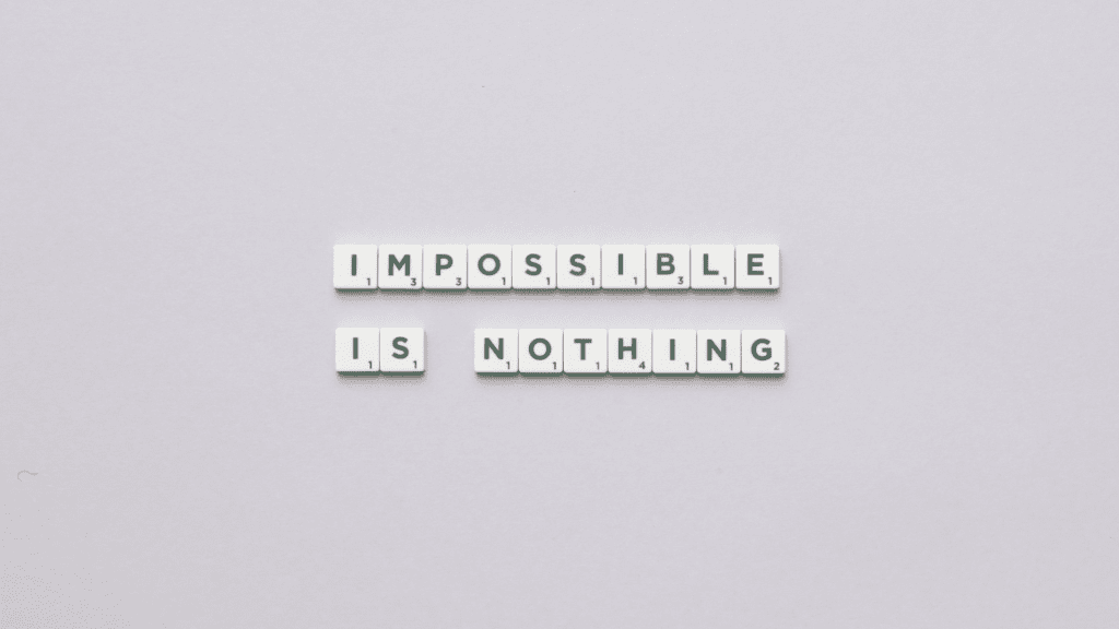 Scrabble tiles spell out "Impossible is Nothing," symbolizing a leader’s ability to overcome obstacles in leadership through mindset shifts.


