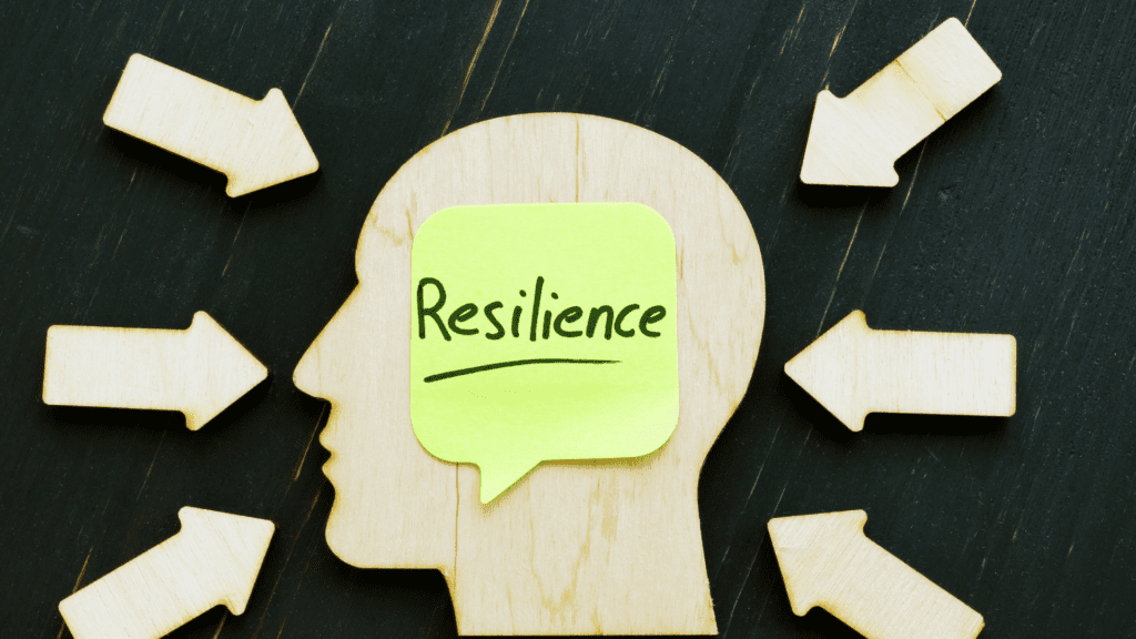 A wooden brain cutout with a sticky note labeled "Resilience," representing the neuroscience behind overcoming obstacles in leadership.


