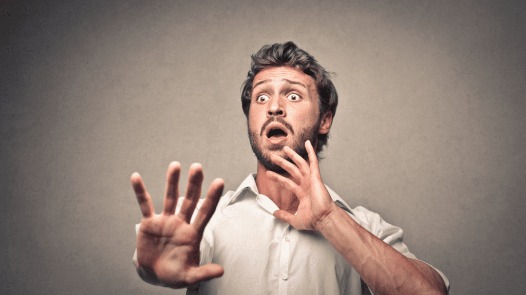 A man with his hands raised defensively, portraying the physical response to fear and anxiety and paradoxical intention techniques.