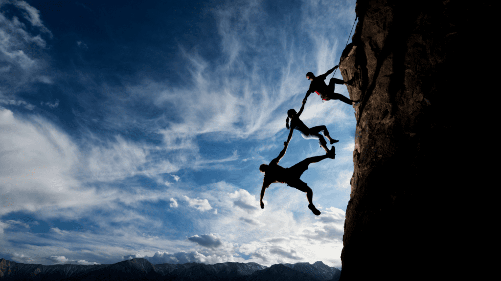 Climbers reaching out to help each other on a steep mountain, symbolizing trust, teamwork, and resilience.