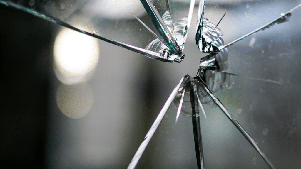 Shattered glass with sharp cracks, representing the fragility of trust and the pain of betrayal.