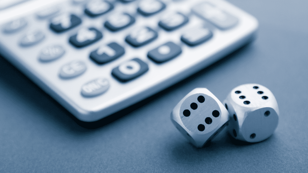 A close-up of a calculator with two dice, symbolizing the balance between strategy and risk-taking in business decision-making.
