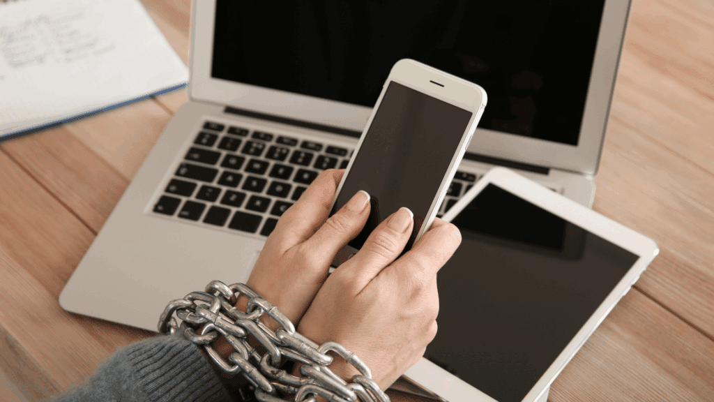 Modern technology dependency symbolized by hands chained to smartphone in a person who has a dopamine addiction.



