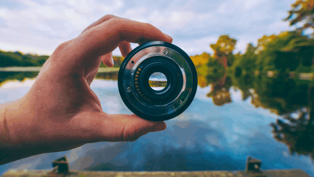 The Neuroscience of Perspective: How Your Brain Shapes the Way You See the World 2 Hand holding camera lens over lake, symbolizing focus in the neuroscience of perspective