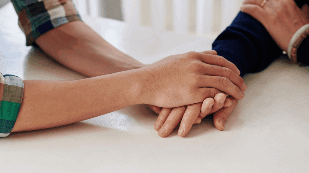 Close-up of hands holding each other as part of reassurance-seeking support



