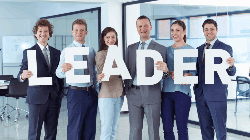 Professionals in business attire holding large letters spelling leader, representing executive presence in the workplace.



