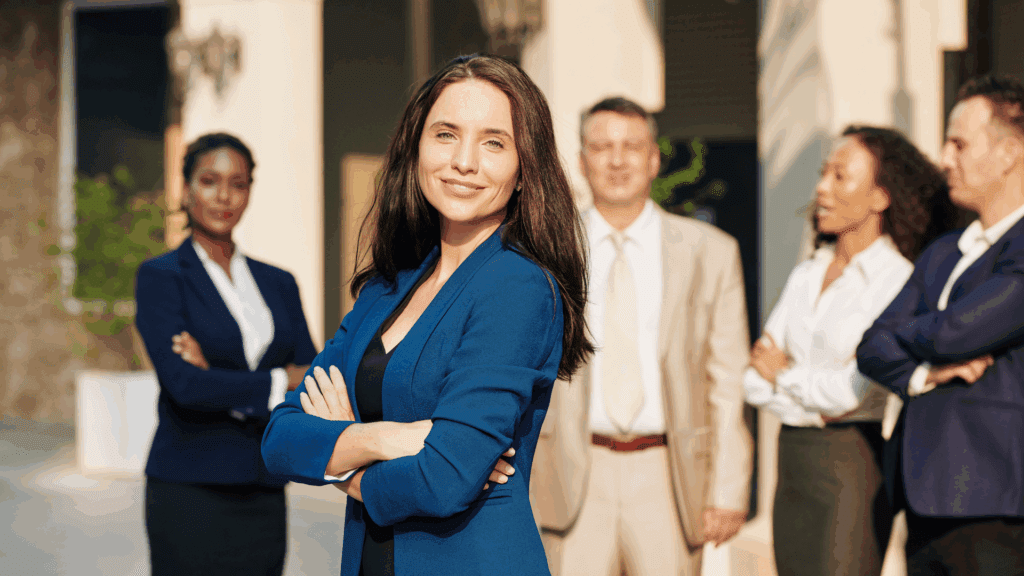 Confident businesswoman standing with her team, showcasing executive presence and leadership impact.






