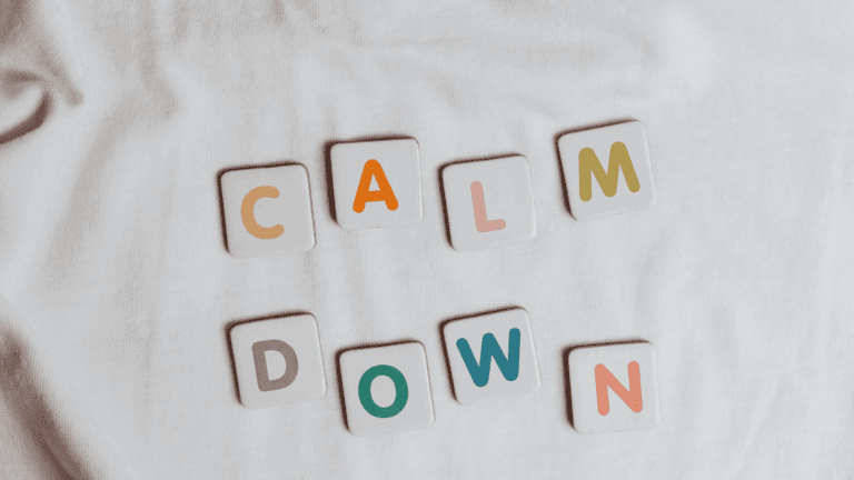 On the Blog 5 Tiles spelling out “calm down” on a white fabric background, symbolizing mindfulness of anxiety and emotional regulation.