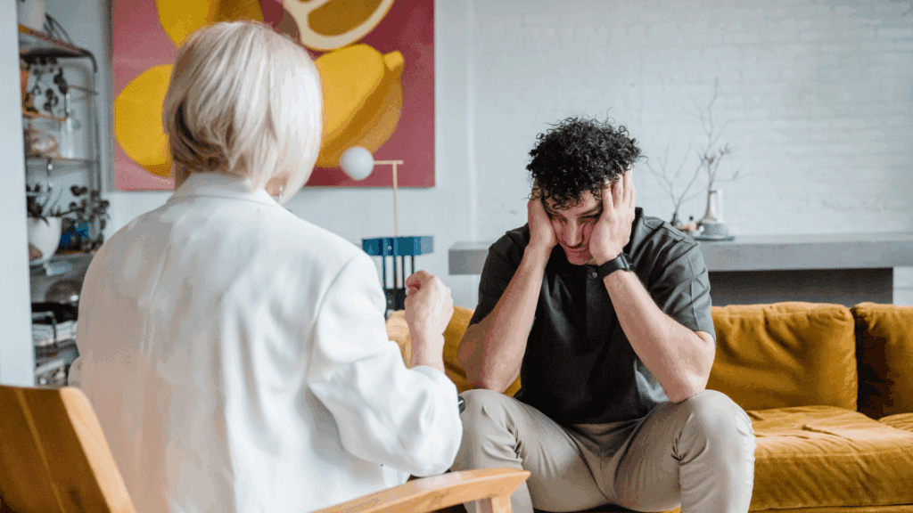 A traditional therapy session without neuroplasticity coaching where the male patients is frustrated holding his head in his hands.