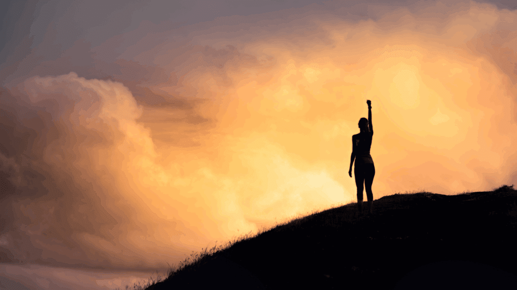  Silhouette of a triumphant person on a hill at sunset, symbolizing the achievement possible through mindset mastery




