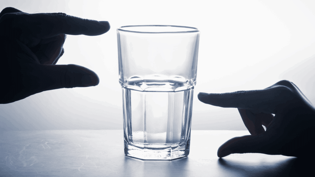 Two hands framing a glass of water, symbolizing perspective in the neuroscience of mental toughness.

