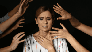Woman feeling overwhelmed and distressed with many hands reaching toward her, symbolizing the struggles of anxious depression.