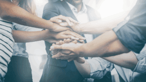 Team members stacking hands together, symbolizing collaboration and connection in Brain-Based Learning.
