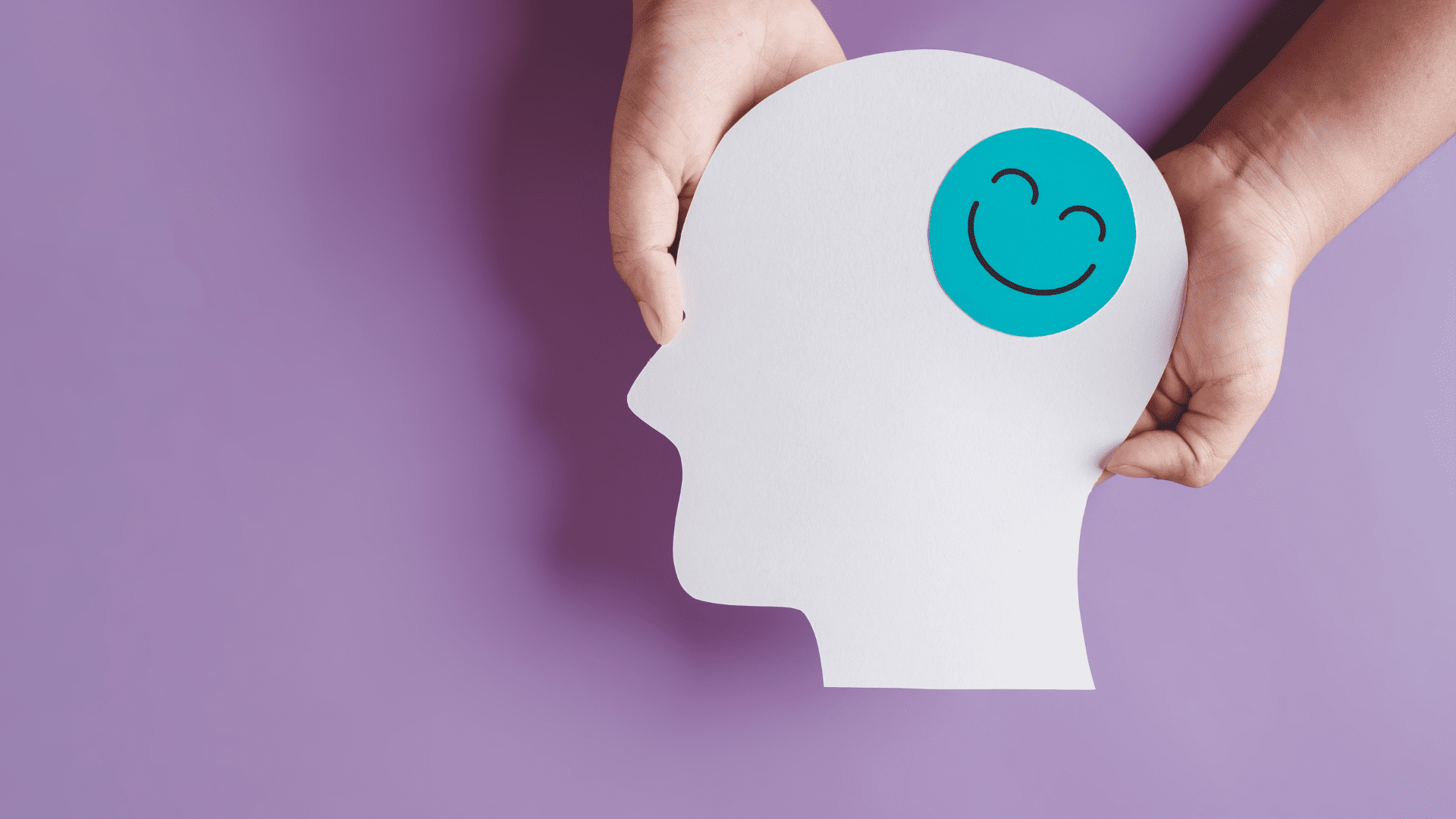 Paper cutout of a human head with a happy face symbol, representing the dopamine paradox in brain reward systems.
