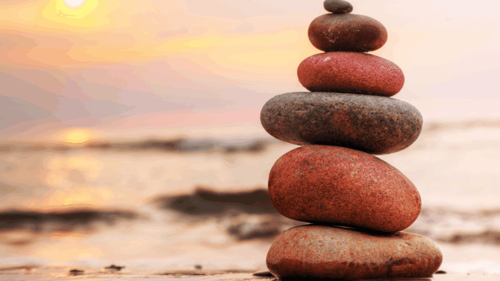 Stacked stones at sunset symbolizing balance, mindfulness, and the choice to escape hustle culture.