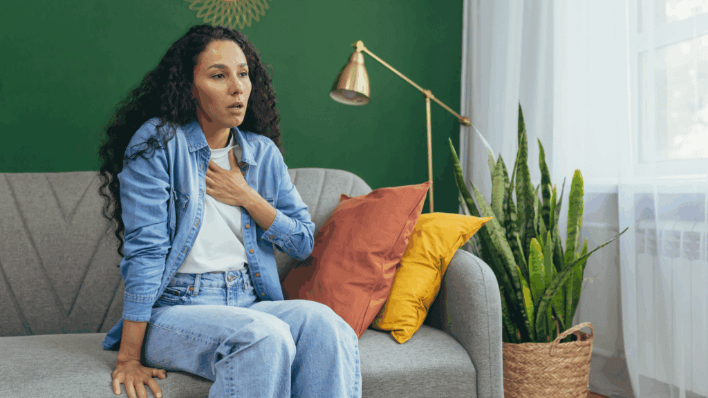 The Science of Calm: How to Stop a Panic Attack with Your Brain’s Help 1 Woman practicing deep breathing on a couch, illustrating techniques for how do I stop a panic attack naturally.