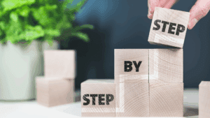 The Neuroscience of Micro-Changes: How Tiny Steps Transform Everything 3 Wooden blocks stacked to form the phrase step by step, symbolizing the neuroscience of micro-changes.