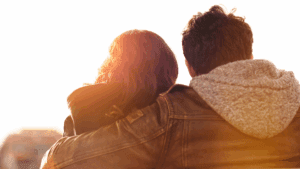 Couple embracing at sunset, symbolizing the emotional difference between wanting versus needing in relationships.