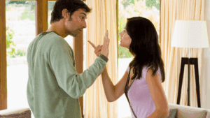 Couple arguing in a living room, representing the emotional conflict between alpha vs beta traits in relationships.