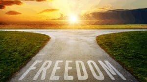 Pathway splitting under a sunrise with the word “freedom,” symbolizing the journey toward embracing your authentic self.