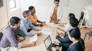 Dopamine-Aware Leadership: Neuroscience for Motivating Teams 3 “Diverse business team in discussion around a meeting table, symbolizing balance and engagement in Dopamine-Aware Leadership.”