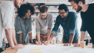 “Diverse team collaborating enthusiastically around a table, representing teamwork driven by Dopamine-Aware Leadership.”