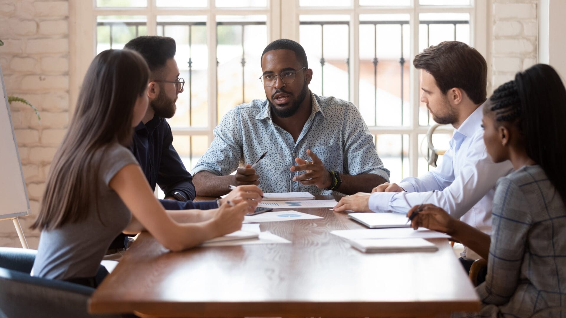 “Business leader guiding a diverse team during a meeting, demonstrating collaboration through Neuroscience-Based Executive Coaching.”