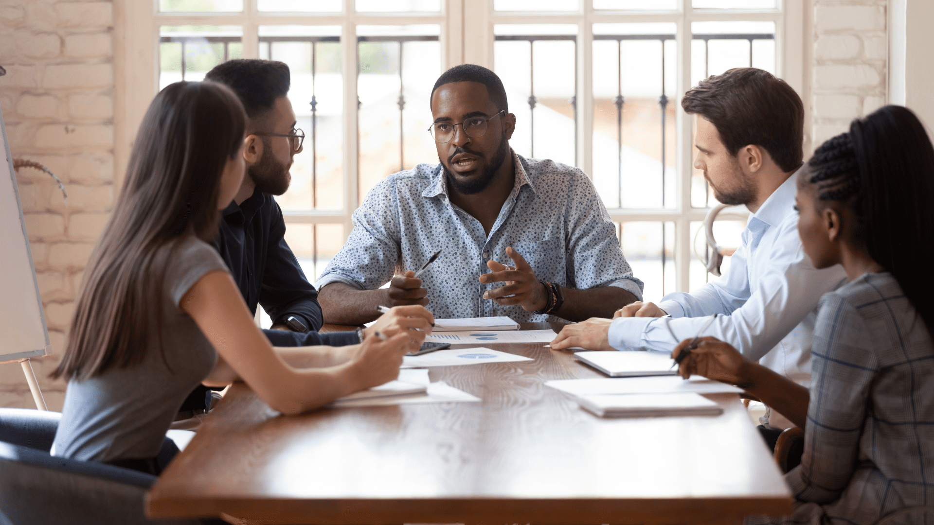 “Business leader guiding a diverse team during a meeting, demonstrating collaboration through Neuroscience-Based Executive Coaching.”