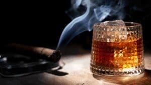Glass of whiskey and cigar on a table, symbolizing traditional masculinity and why men struggle with intimacy.