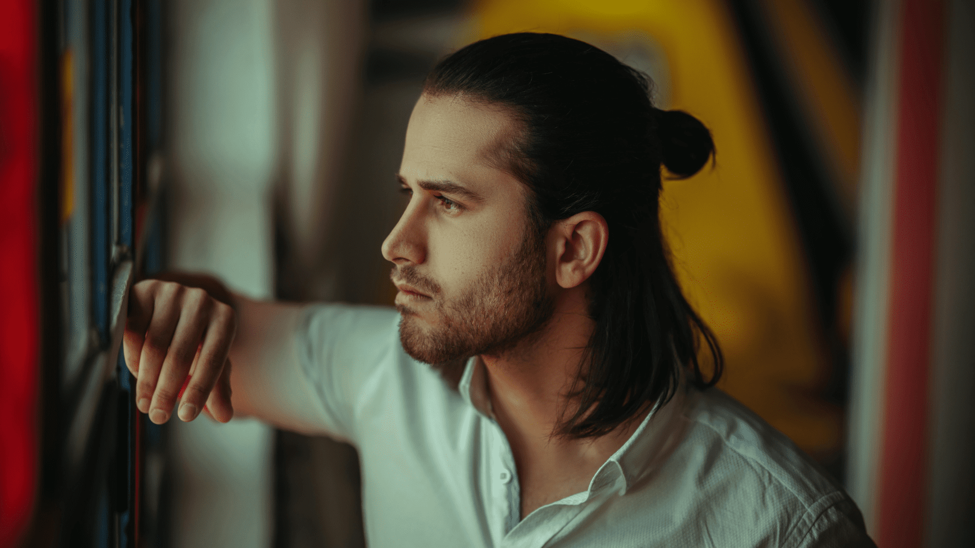 Thoughtful man looking out the window, symbolizing desire and reflection on why we want what we can't have.